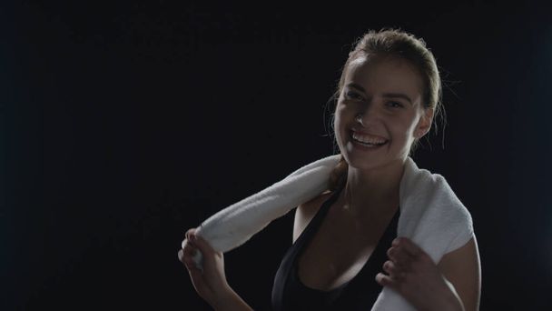 Siyah arka planda poz veren omuzlarında havlu olan sporcu kadın. Fitness modeli - Fotoğraf, Görsel