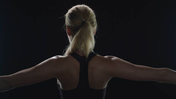 Back view of sport woman training stretch exercise in gym. Fit girl warming up - Foto, Bild