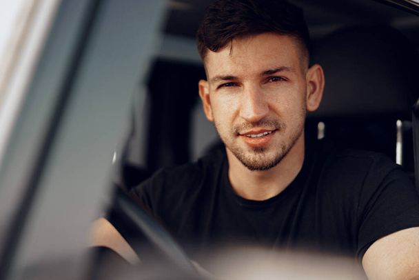 Handsome young man driver looking through the window of his off-road car - 写真・画像