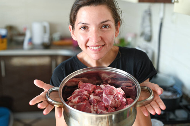 Chica sosteniendo una cacerola con carne. Foto de alta calidad - Foto, Imagen