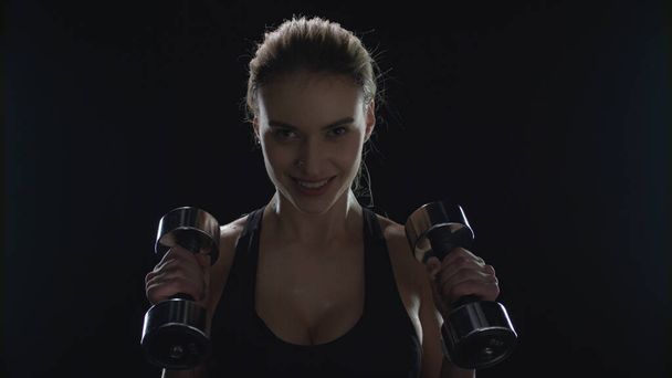 Sportovní žena trénink s činkami během sportovního cvičení v tmavé tělocvičně - Fotografie, Obrázek