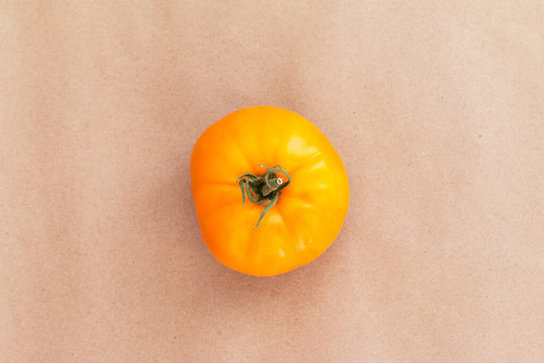 Yellow big tomato isolated on beige color background - Фото, изображение