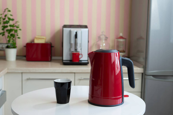 Red kettle and a black cup on a kitchen table - Photo, Image