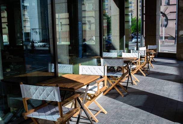 Puste krzesła i stoliki przed kawiarnią. Miejski taras letni - Zdjęcie, obraz