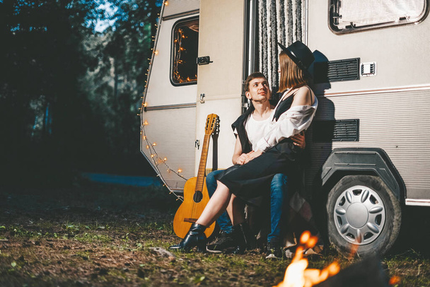 Havalı kıyafetler içinde genç bir çift romantik bir haftasonu tatili Orman Yolu 'ndaki kampçının arka planına karşı. - Fotoğraf, Görsel