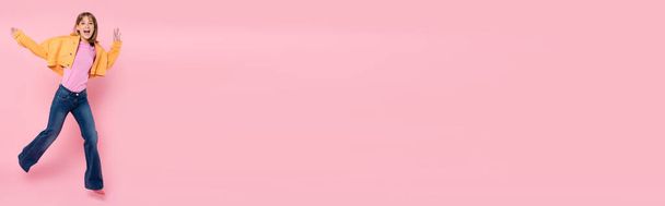 Panoramic shot of woman looking at camera and jumping on pink background - Fotoğraf, Görsel