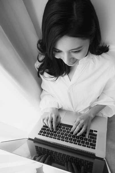 jong aziatische vrouw met behulp van computer thuis in zwart-wit - Foto, afbeelding