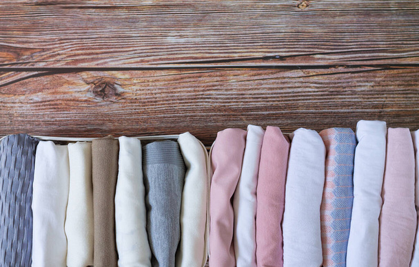 Almacenamiento vertical de ropa. Cajas de armario organizador con vista superior a la ropa en mesa de madera - Foto, imagen