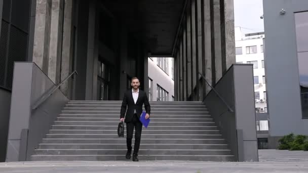Portret van jonge positieve vrolijke succesvolle zakenman met aktetas grappig dansen en springen van vreugde tijdens het lopen uit kantoor - Video