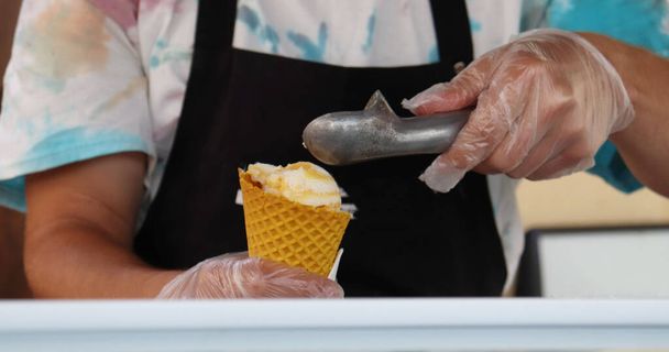 Verkäufer füllt Eis in Waffelbecher. - Foto, Bild