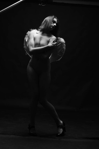 beautiful nude woman wearing decorative angel wings posing on dark background     - Photo, image