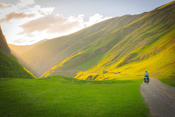Ciclista en la carretera de grava rodeada por las montañas que van al valles. Vida sana y actividades recreativas. - Foto, Imagen