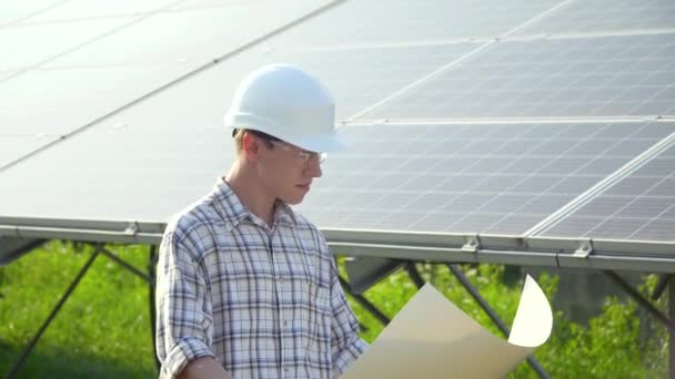 Engineer in a white helmet is at the solar power station. Green energy concept - Felvétel, videó