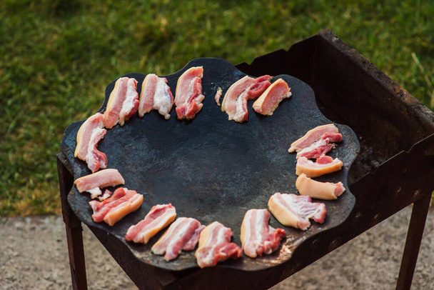 fried bacon. Bacon strips or rashers being cooked in frying pan. Bacon Sizzling on Skillet - Photo, Image
