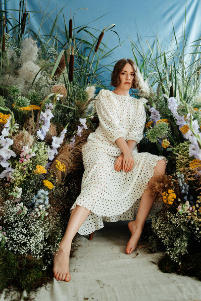Κορίτσι μοντέλο με όμορφο χτένισμα και μακιγιάζ σε λευκό φόρεμα με λουλούδια σε μια αίθουσα μόδας στυλ για το περιοδικό Vogue - Φωτογραφία, εικόνα