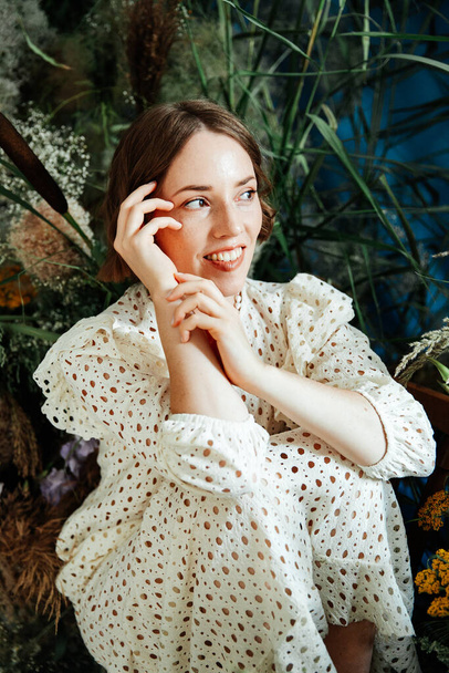 Mädchen-Modell mit schöner Frisur und Make-up in einem weißen Kleid mit Blumen in einem Mode-Stil Raum für Mode-Magazin - Foto, Bild
