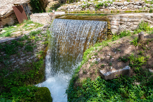 Piccolo makes water and forms a small waterfall on a sunny day - Photo, Image