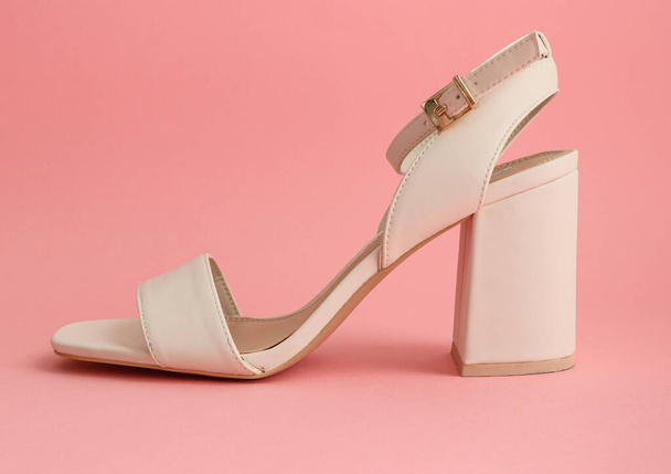 sapatos de salto altoUma sandália branca com salto alto quadrado fica em um fundo rosa, vista lateral close-up
. - Foto, Imagem