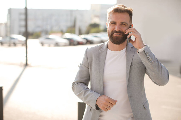 Portrait of a man with beard and phone outdoor - Photo, Image
