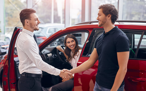 Client and manager making agreement in car dealership - Foto, imagen
