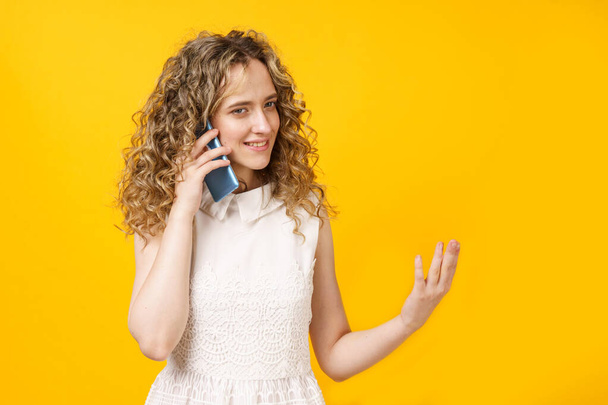 Telefonda duygusal olarak konuşan genç bir kadının portresi. Kadın portresi. Sarı arkaplanda izole edilmiş - Fotoğraf, Görsel