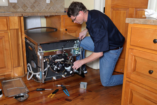 Технік по ремонту посудомийної машини працює на зламаній посудомийній машині
 - Фото, зображення