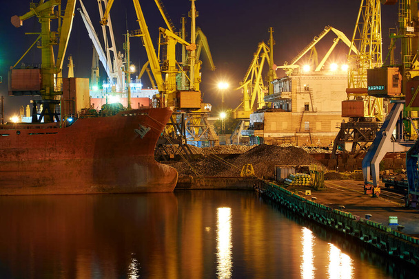 zicht op de industriële haven 's nachts - schepen wachten op laden en lossen, vrachtvervoer over zee - Foto, afbeelding