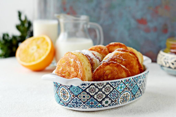 Yeast pancakes in powdered sugar with milk and honey on a light background. Yeast fritters for Sunday breakfast - Photo, Image