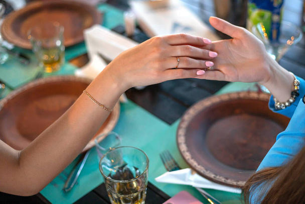 Egy nő eljegyzési gyűrűt mutat egy másik nőnek az asztalnál egy étteremben.. - Fotó, kép