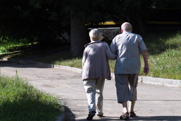 пожилые мужчина и женщина, идущие по тропинке в парке - Фото, изображение