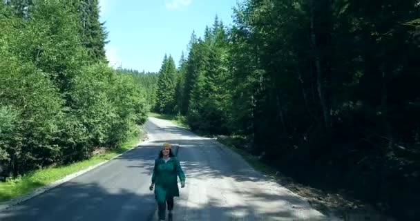Vrouwen die alleen in het midden van de bosweg lopen en weglopen van de auto - Video
