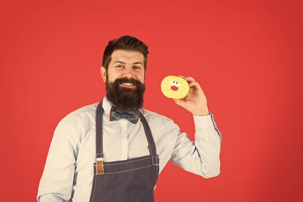 Bearded well groomed man in apron selling donuts. Donut food. Baked goods. Sweets and cakes. Junk food. Hipster bearded baker hold donuts. Eat donut. Cheerful mood. Doughnut calories. Glazed donut - Foto, Imagen