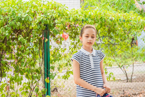 Una niña que se prepara para ir a la escuela. Una chica con uniforme escolar y mochila. Adolescente en otoño en el patio escolar - Foto, Imagen