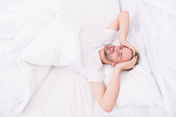 Sleep problems can lead to headaches in morning. Handsome man relaxing in bed. Snoring can increase risk headaches. Common symptom of sleep apnea. Causes of early morning headache. Migraine headaches - Fotó, kép