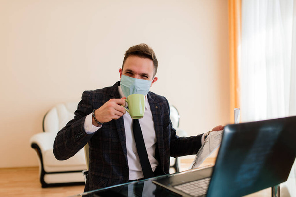 Photo of young handsoma businessman with notebook freelance job internet, want get job quarantine stay home, wear facial medical mask - Фото, изображение