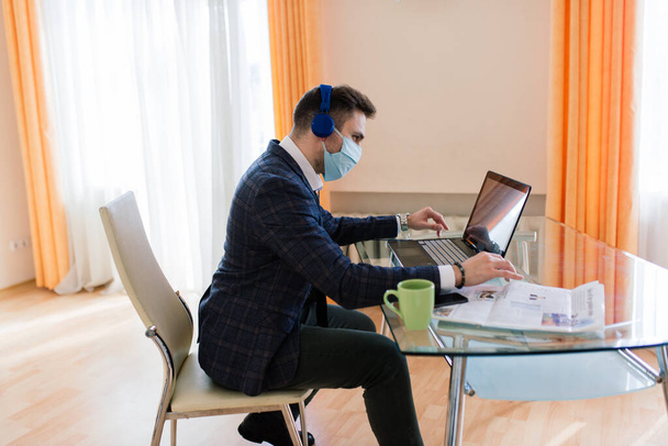 Фото молодого бізнесмена з ноутбуком позаштатний робочий інтернет, хочете отримати роботу карантину залишатися вдома, носити медичну маску для обличчя
 - Фото, зображення