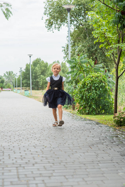 Una ragazzina che si prepara ad andare a scuola. Una ragazza in uniforme scolastica con uno zaino. Adolescente in autunno nel cortile della scuola - Foto, immagini