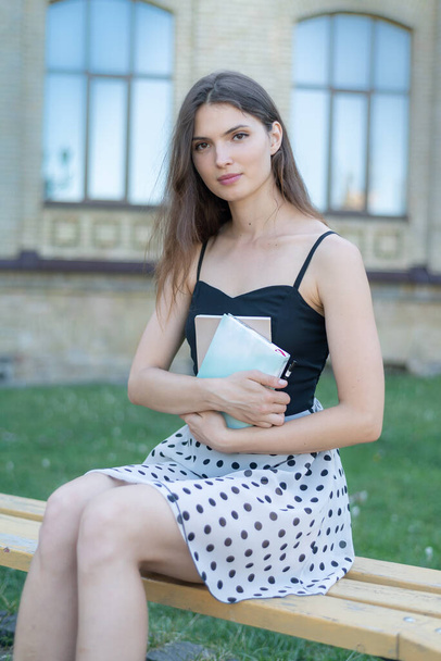 Girl student with a book and a notebook on a bench near the university. Kyiv. Ukraine - Fotoğraf, Görsel