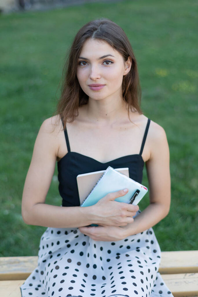 Studentka s knihou a zápisníkem na lavičce u univerzity. Kyjev. Ukrajina - Fotografie, Obrázek