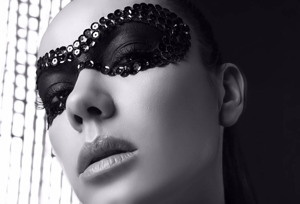 Close-up portrait of charming elegant brunette woman in sequins mask posing on black background in studio - Foto, immagini