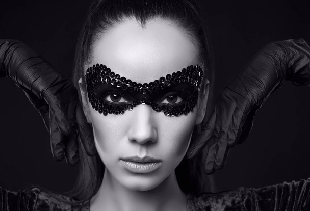 Gros plan portrait de charmante femme brune élégante en paillettes masque et gants posant sur fond noir en studio - Photo, image