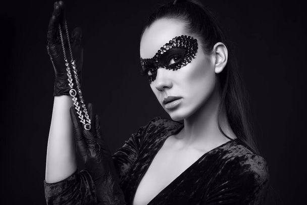 Portrait of charming elegant brunette woman in beautiful purple dress and sequins mask with black gloves looks at a stolen diamond necklace - Photo, Image
