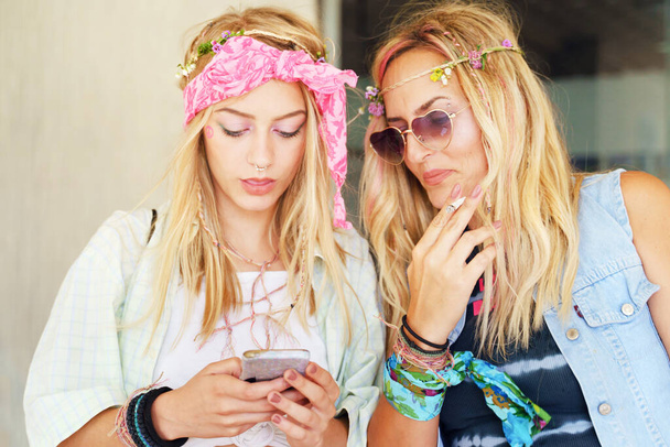 Beautiful young caucasian woman typing message with mother - Two blonde sisters friends using mobile phone in day - Girls use smartphone for communication or internet - real people city life concept - Photo, Image