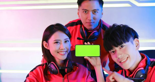 Team of asian teenage cyber sport gamers  show app game on the 5g smartphone with green screen - Zdjęcie, obraz