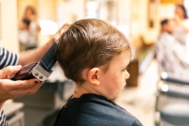 Nuori poika parturissa saada hiustenleikkuun - Valokuva, kuva
