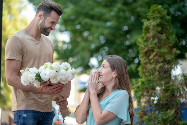 Bearded male presenting bouquet of flowers to surprised female - Photo, Image