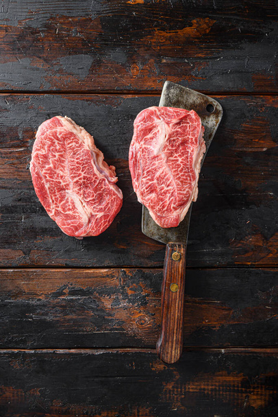 Flaches eisernes Steak, rohes Fleisch, marmoriertes Rindfleisch Oberklingenfutter geschnitten auf metallischem Metzgerspaltmesser von oben Ansicht vertikal. - Foto, Bild