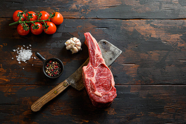 Raw market beauty  steak on meat cleaver. Organic farm marbled prime black angus beef. Dark wooden background. top view. With seasonings, peppercorns, rosemary,salt,garlic. space for text - Фото, зображення