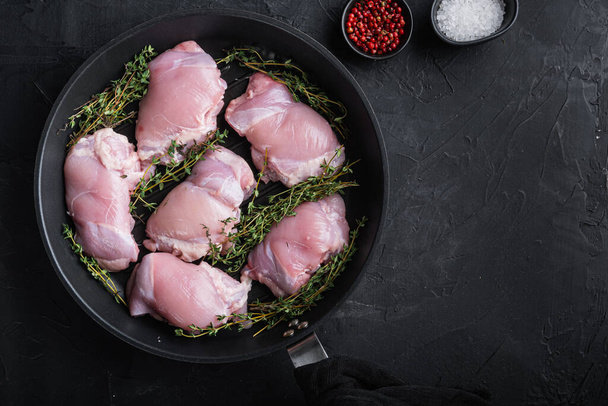 Сырое куриное мясо на сковороде на черном фоне с пробелами для текста. - Фото, изображение