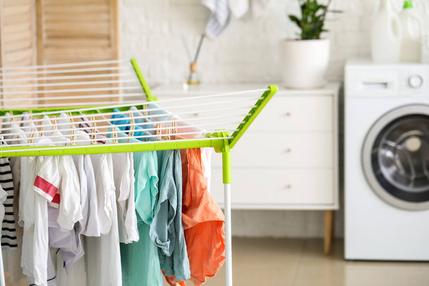Clean clothes hanging on dryer in laundry room - 写真・画像